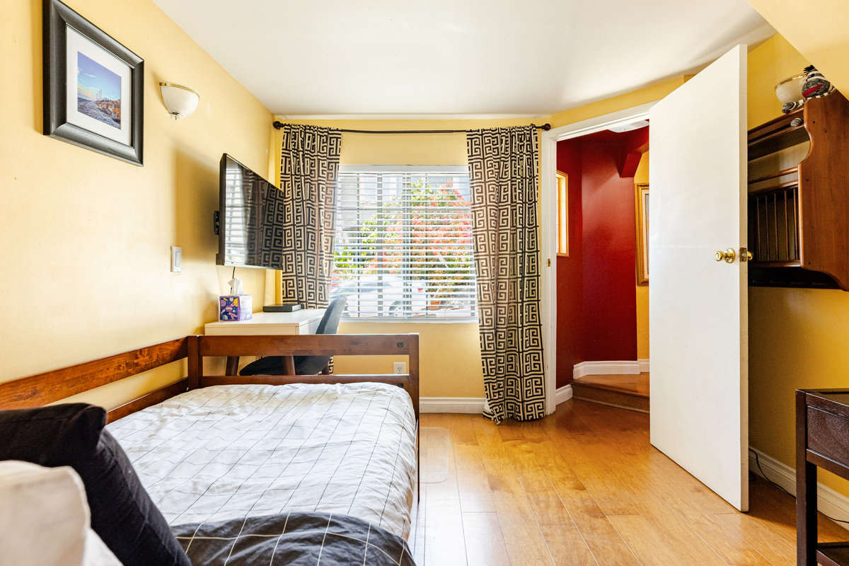 View of 2nd bedroom twin beds, laptop workstation and wall mounted TV