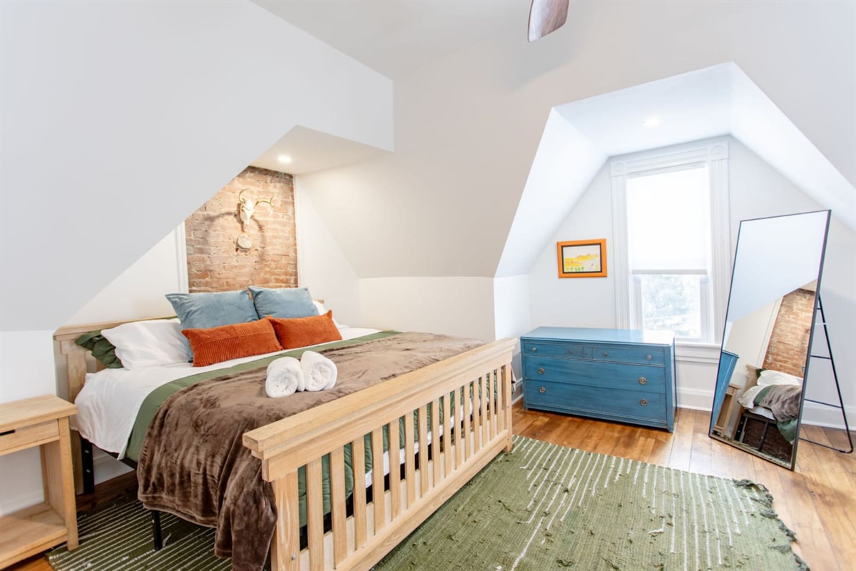 A stylish bedroom featuring a spacious king-sized bed, complemented by a full-length mirror that adds depth and elegance to the room, enhancing both the aesthetic and functionality of the space.