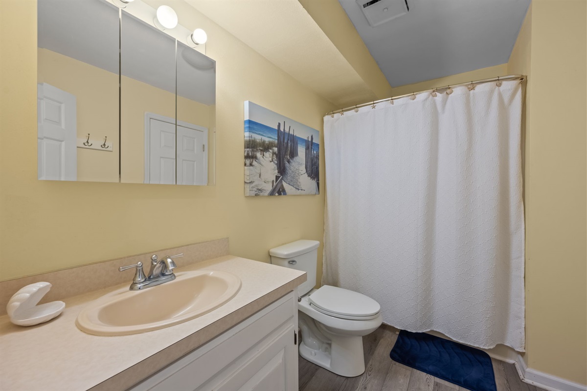 Full bathroom with vanity lighting and a shower tub combo, perfect for rinsing off after time at the beach