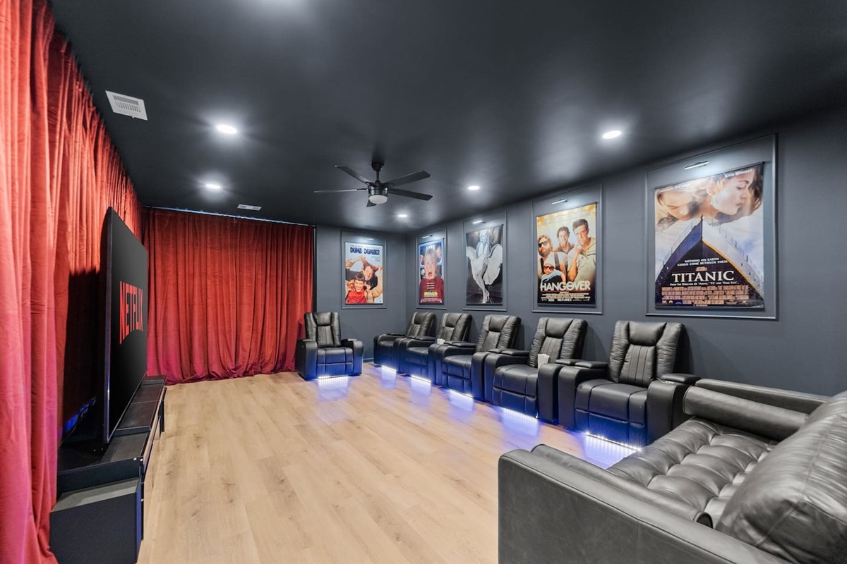 Private home theater with a large screen, plush seating, and dramatic red curtains—perfect for an immersive movie experience.