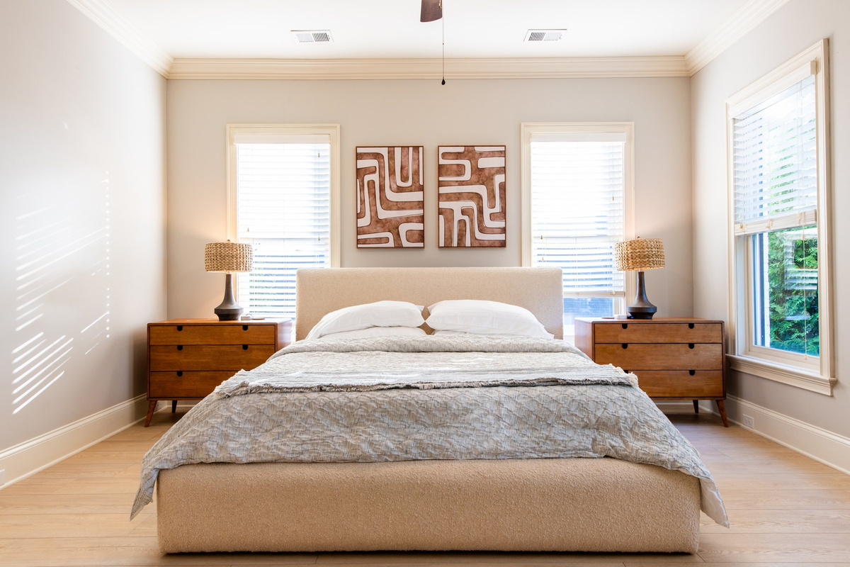 The primary suite features a plush upholstered bed and large windows.