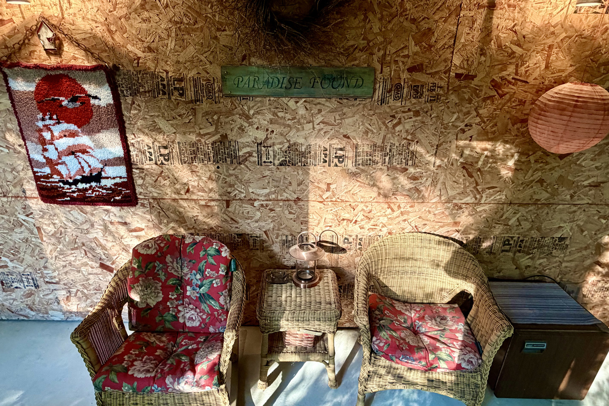Discover "Paradise Found" in the Settler's Sidecar lounge. This inviting layout features cozy wicker armchairs, a convenient snack fridge, and eclectic local art, offering a wonderfully unique, rustic retreat right on the property.