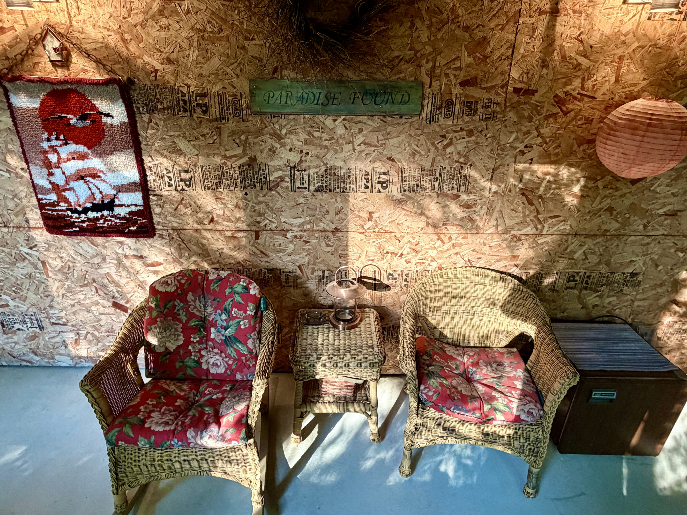Discover "Paradise Found" in the Settler's Sidecar lounge. This inviting layout features cozy wicker armchairs, a convenient snack fridge, and eclectic local art, offering a wonderfully unique, rustic retreat right on the property.