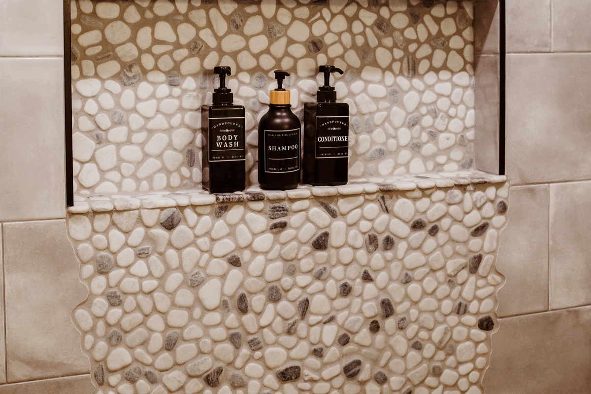 Indulge in a spa-like shower with premium products and designer stone accents.