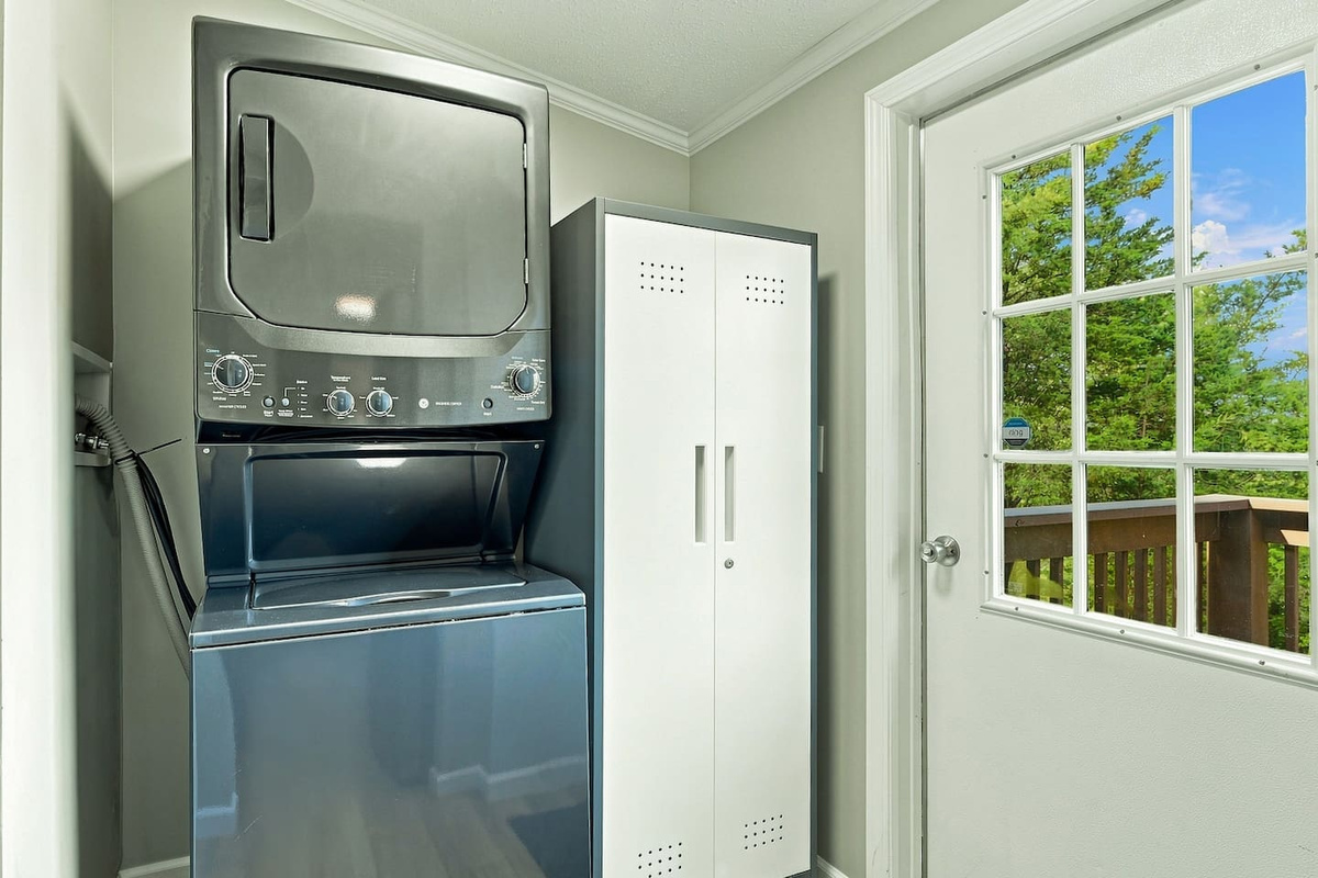 Stacked washer and dryer are available for guest use, along with laundry detergent, dryer sheets, and basic cleaning supplies. Shelving provides additional space for storing groceries and dry goods during your stay.