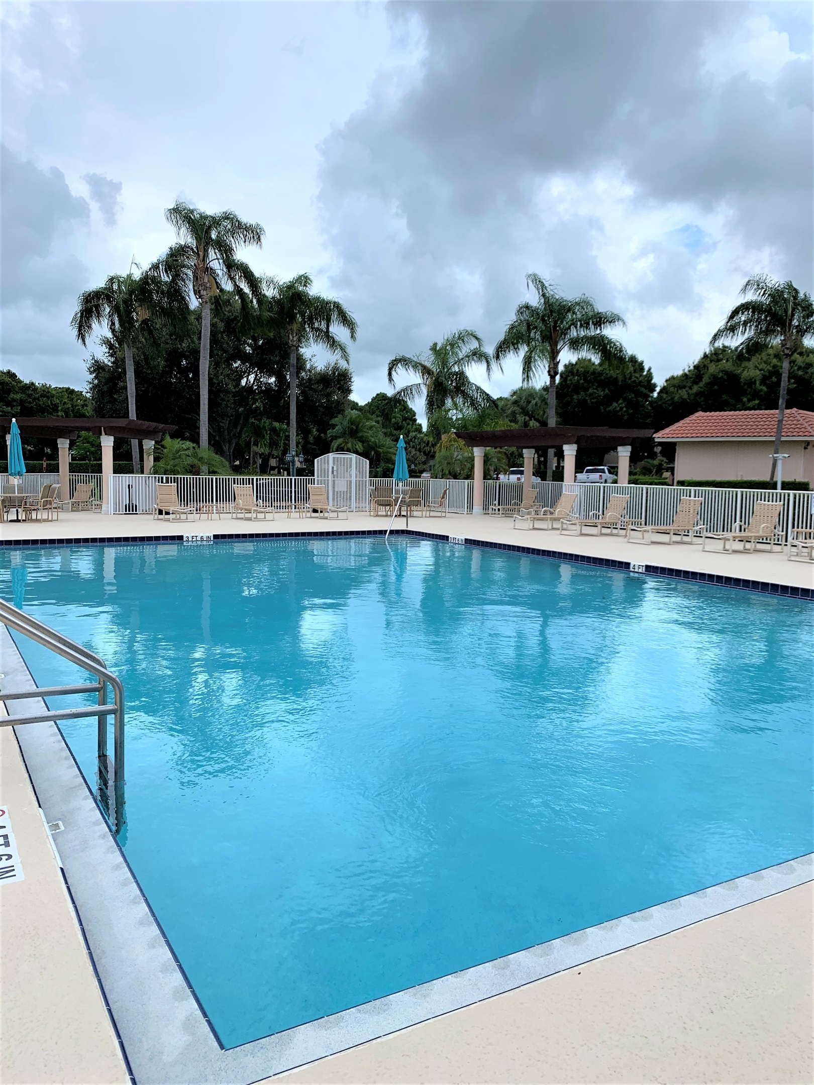 Bright community pool area with lounge seating, umbrellas, and a relaxing resort-style feel.