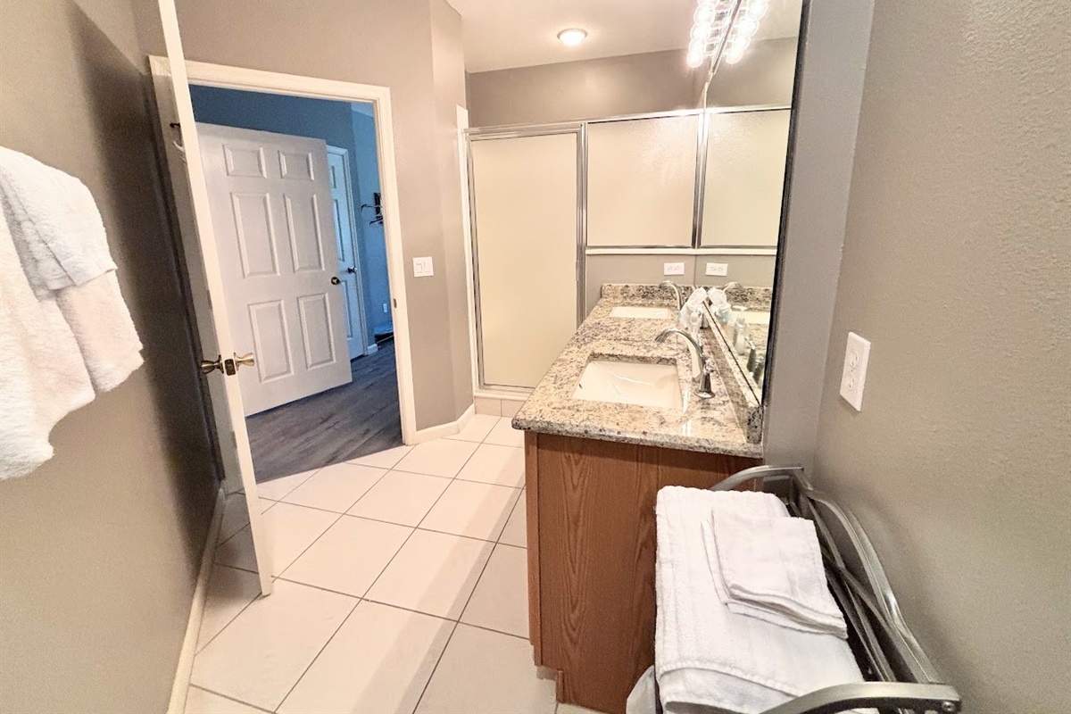 Bright bathroom with large vanity, tile flooring, and a shower enclosure.