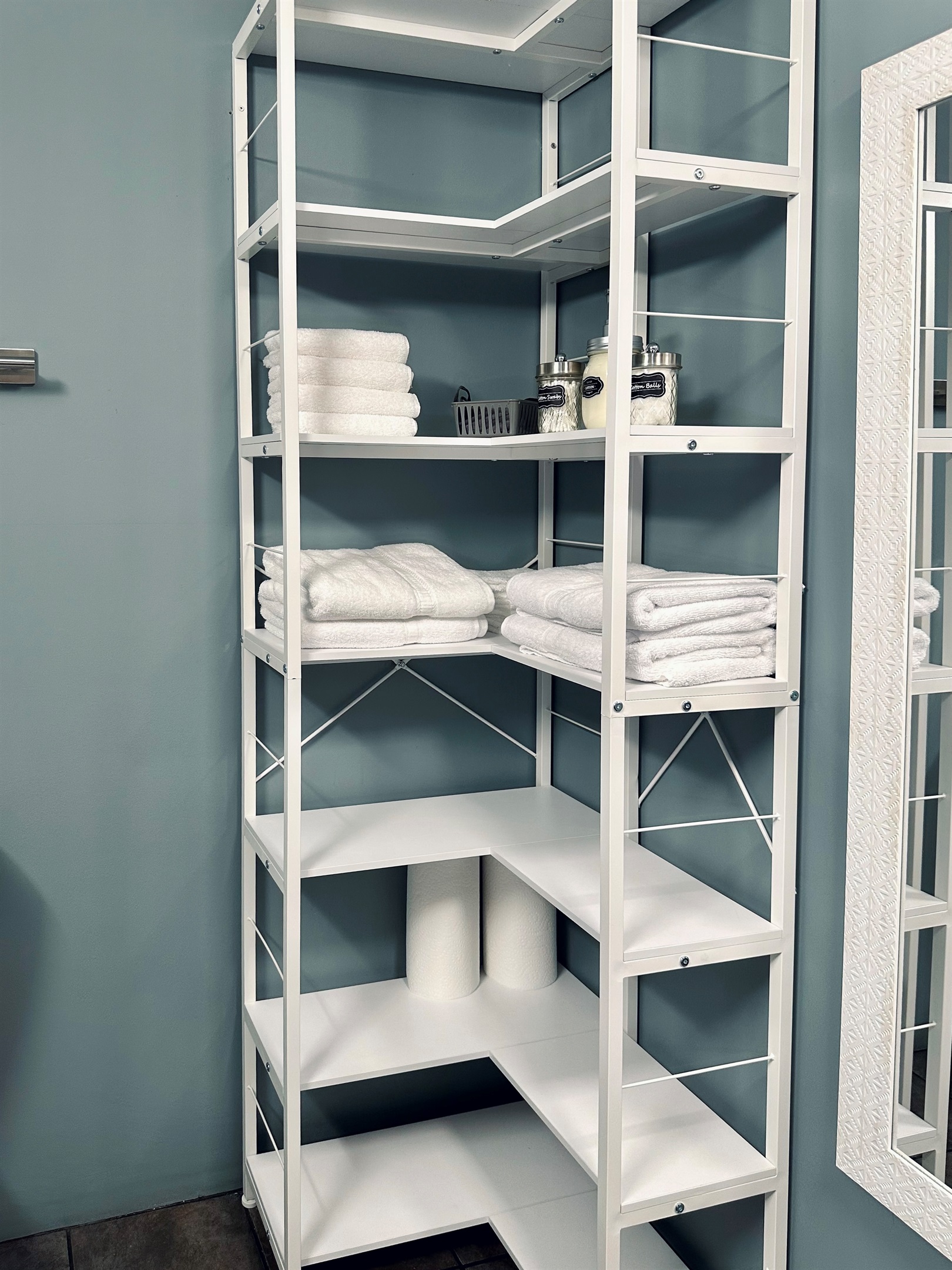 Basement bathroom shelving stocked with fresh bath towels, hand towels, washcloths, and makeup remover cloths. Includes cotton swabs, cotton balls, lotion, and generous additional storage—ideal for guests using the lower-level suite.