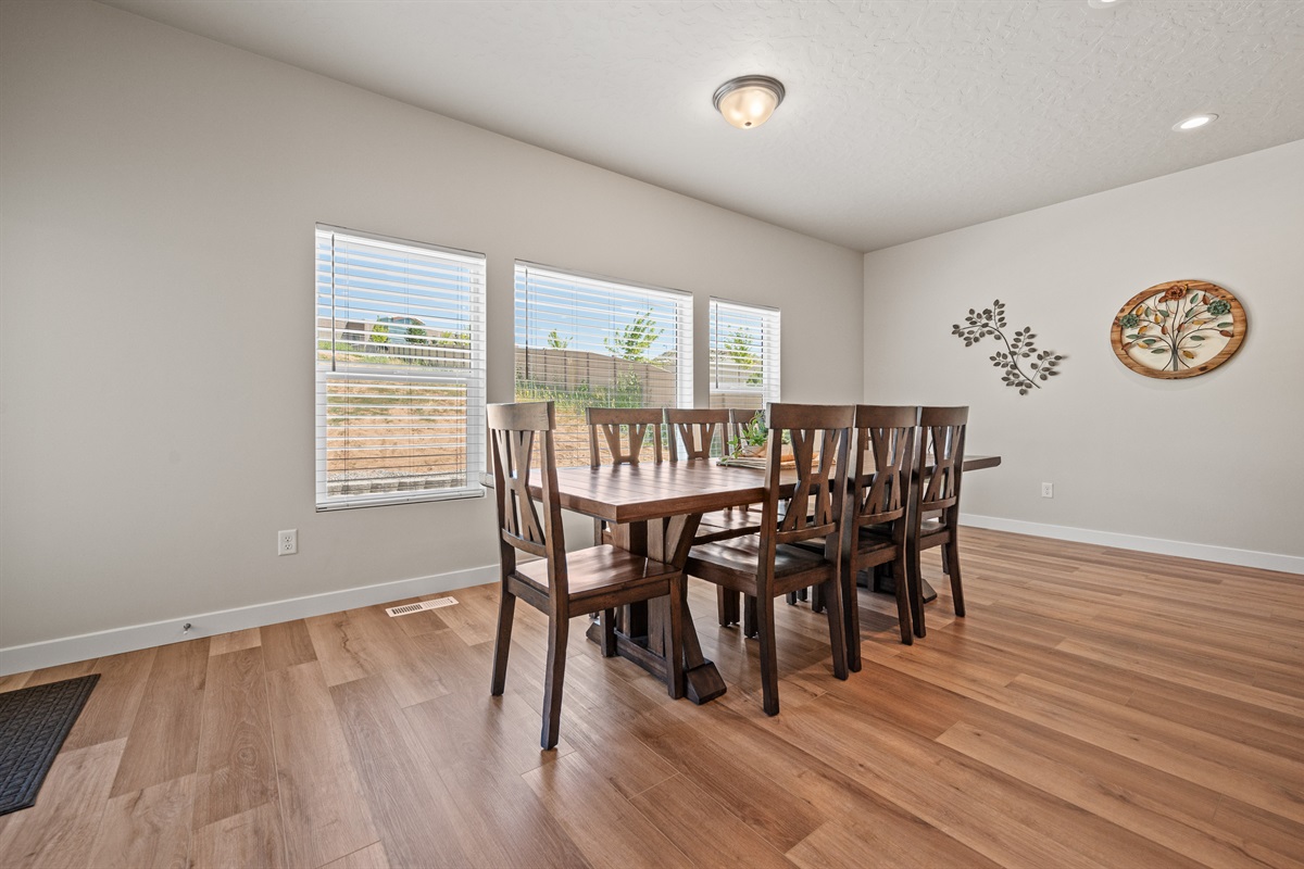 This inviting dining space features a rustic wood table for eight and expansive windows that fill the room with natural light and backyard views.