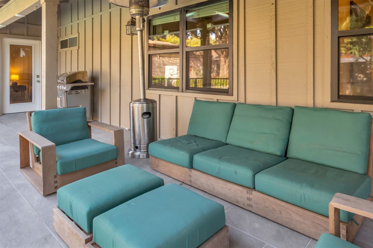 Outdoor sitting area with comfortable furniture, a gas BBQ grill, and propane heaters, creating a cozy and inviting space for relaxing, dining, and enjoying the backyard year-round.