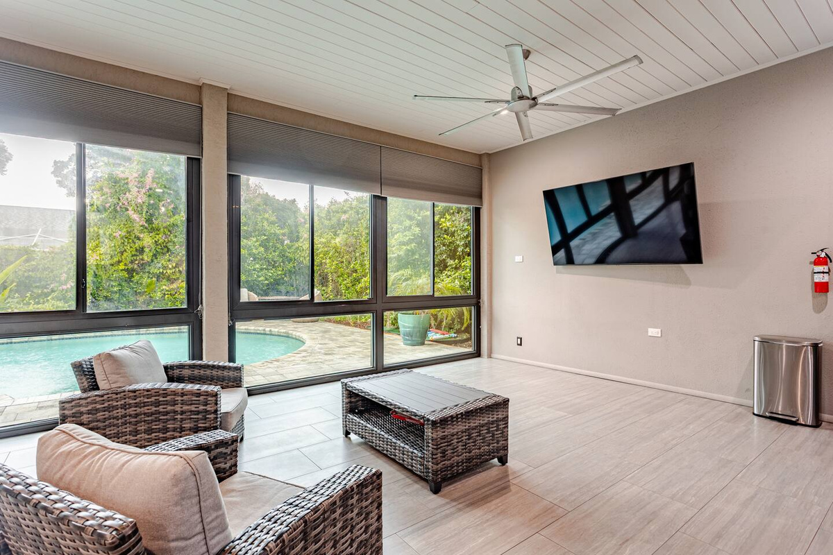 Luxurious, light-filled sunroom featuring a large television, plush lounge chairs, and sophisticated furnishings. A serene and stylish retreat designed for relaxing, entertaining, and enjoying quality time together.
