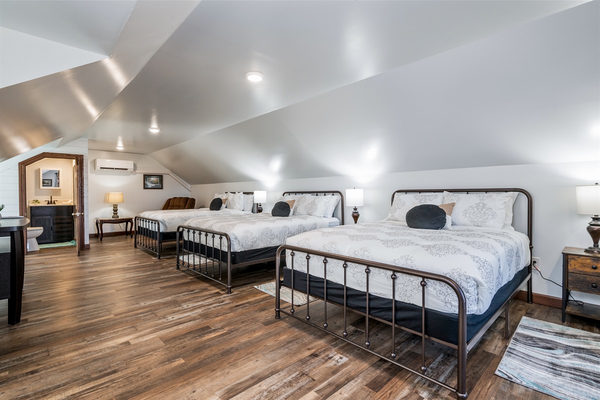 Rest easy in this roomy, modern bedroom featuring cozy beds, sleek flooring, and natural light.