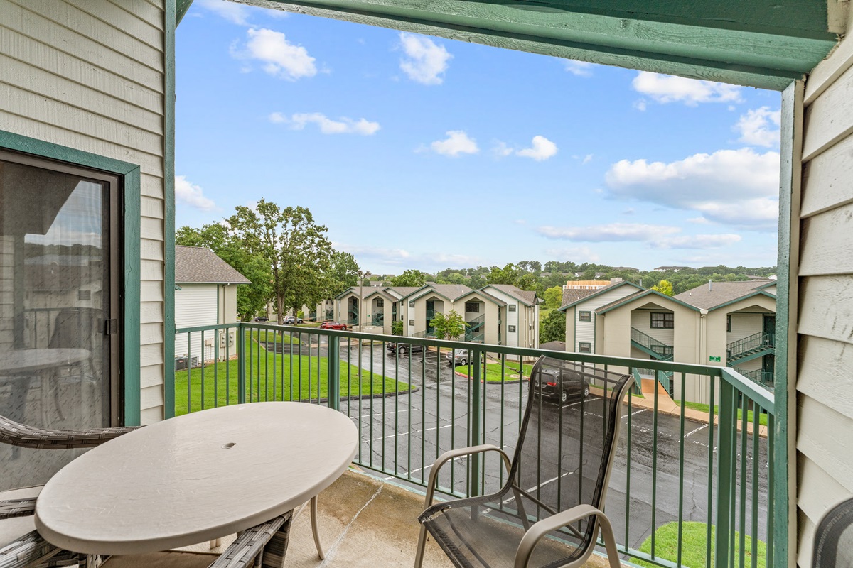 Another balcony angle showing the peaceful view across the grounds and neighboring roofs of The Greens.