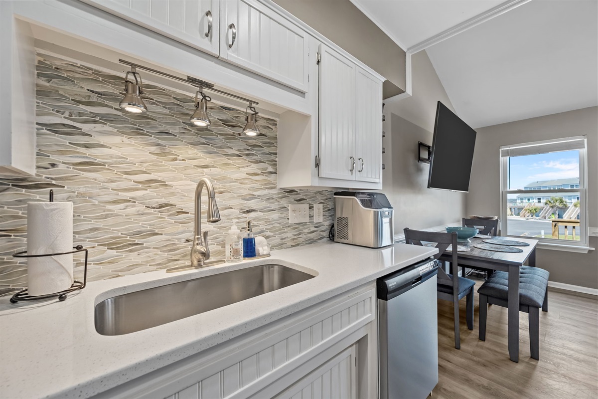 Kitchen sink area with tile backsplash and counter space