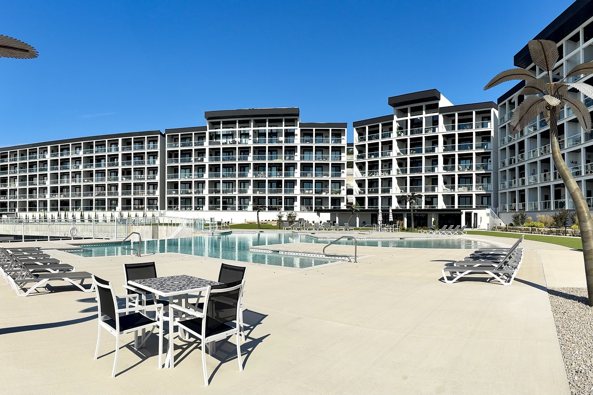 Pool 2 is located outside the community room in front of Building 4. Pool 2 has an infinity-edge waterfall with more loungers and tables/chairs. A set of bathrooms is located near each pool.