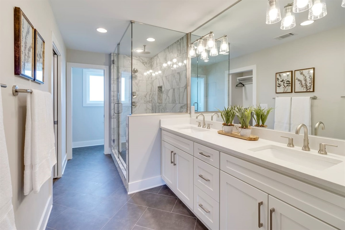 - Double sink vanity with modern brushed nickel fixtures and full wall mirror design - Elegant lighting and decorative greenery bring warmth to the sleek, clean space - Glass enclosed shower and easy layout offer a spa like experience with everyday ease