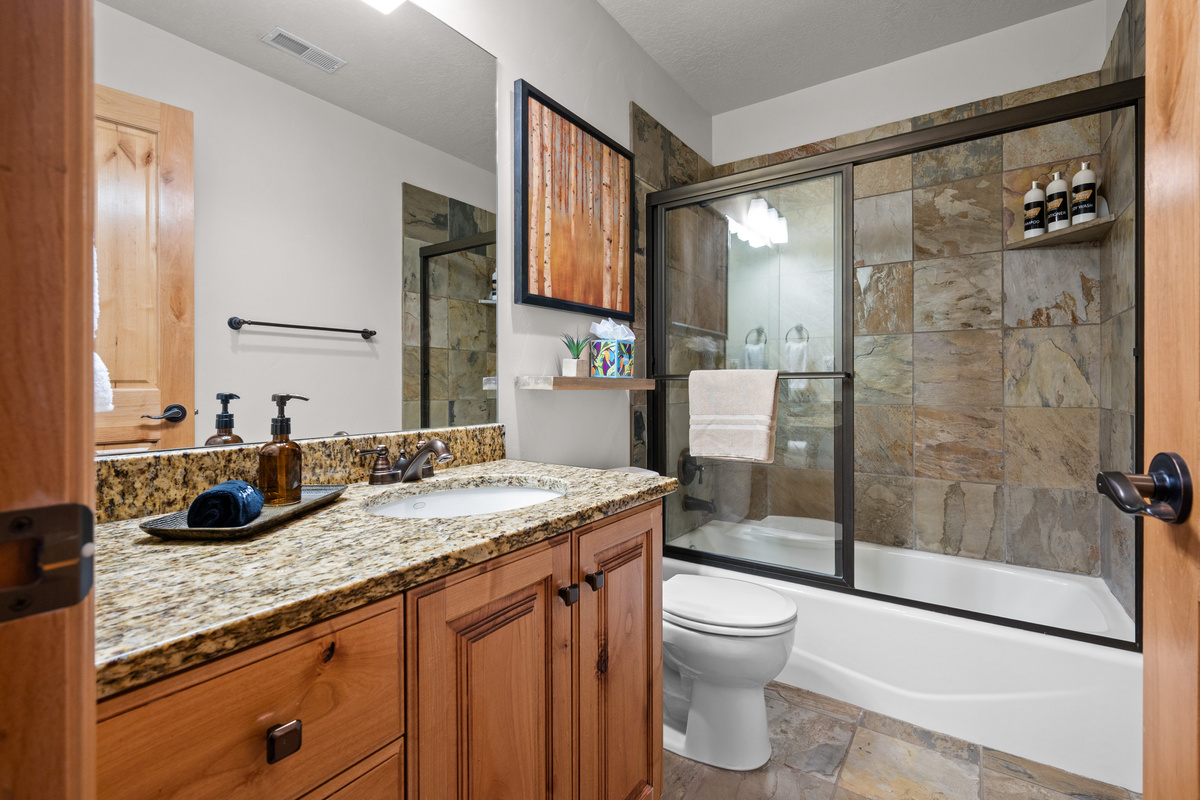 Main floor bathroom with granite vanity and tub/shower combination.