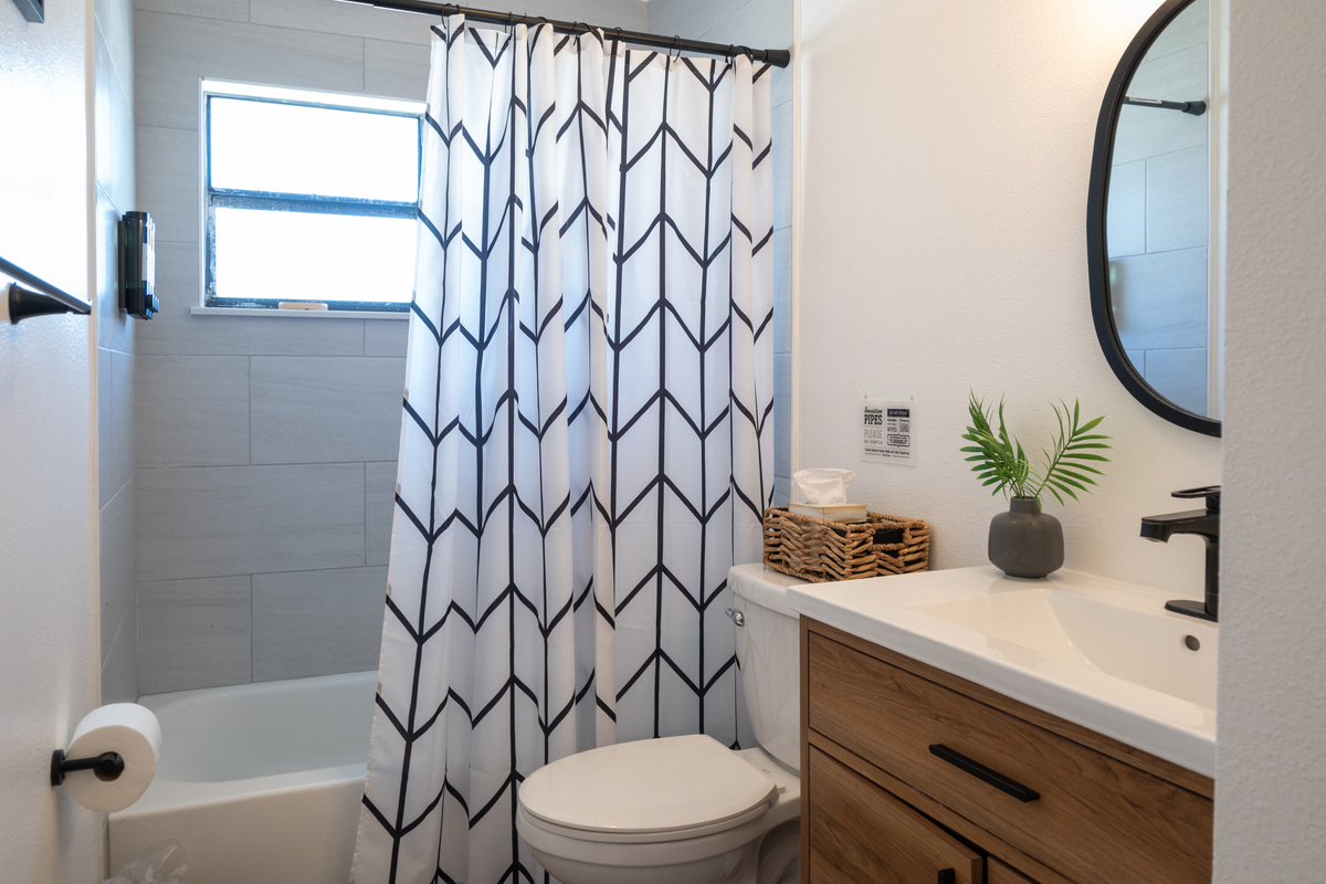 Bathroom with tub/shower combo, modern vanity and hotel-style toiletries