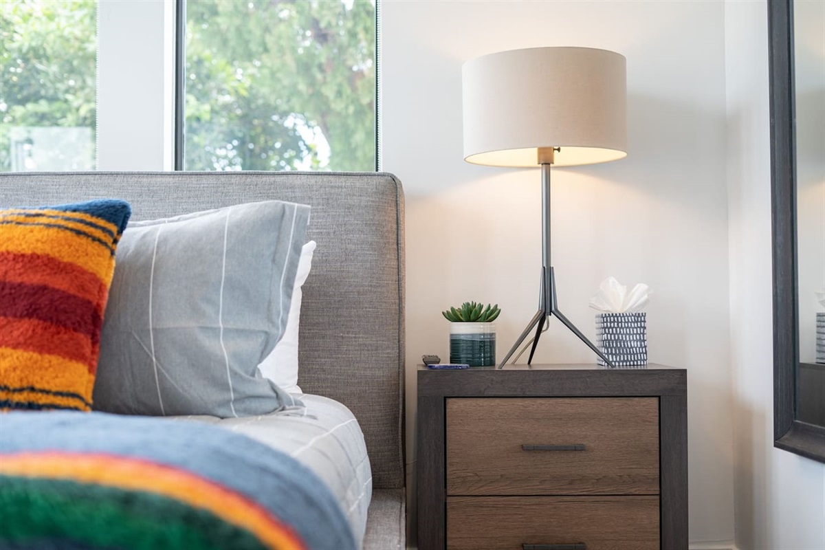 Spacious king bed with cozy sheets and pillows, simple yet stylish decor, and large windows offering plenty of natural light. Complete with a ceiling fan and TV for your relaxation.