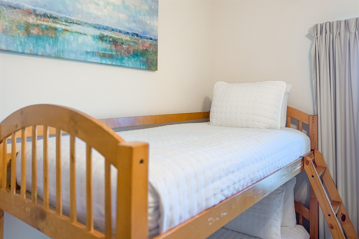 A versatile guestroom featuring a bunk bed and a queen-size bed, ideal for families or friends traveling together, with a comfortable and welcoming atmosphere.