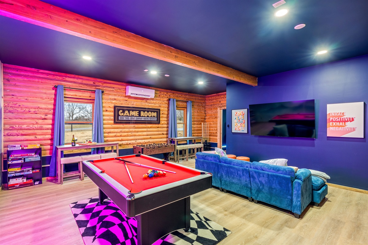 Spacious game room with a pool table, comfy lounge seating, and a TV perfect for relaxing between matches or hosting a movie night.