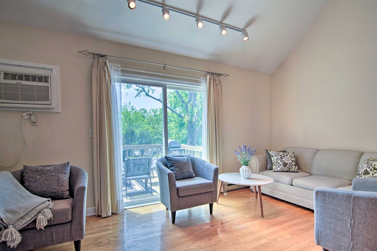 The amply sized, modern living room has plenty of seating for six and also accesses the private deck and gas grill.