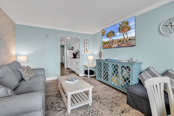 Comfortable living space with sofa seating, flat-screen TV, and easy access to the dining area