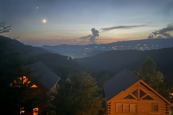 Watch the sun set over layered mountain ridges while town lights twinkle below
Evenings on the deck: sunset skies, a crescent moon, and the whole valley glowing