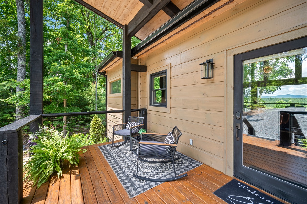 Rocking chairs, tall trees, and timeless tranquility at the front porch. A peaceful atmosphere.