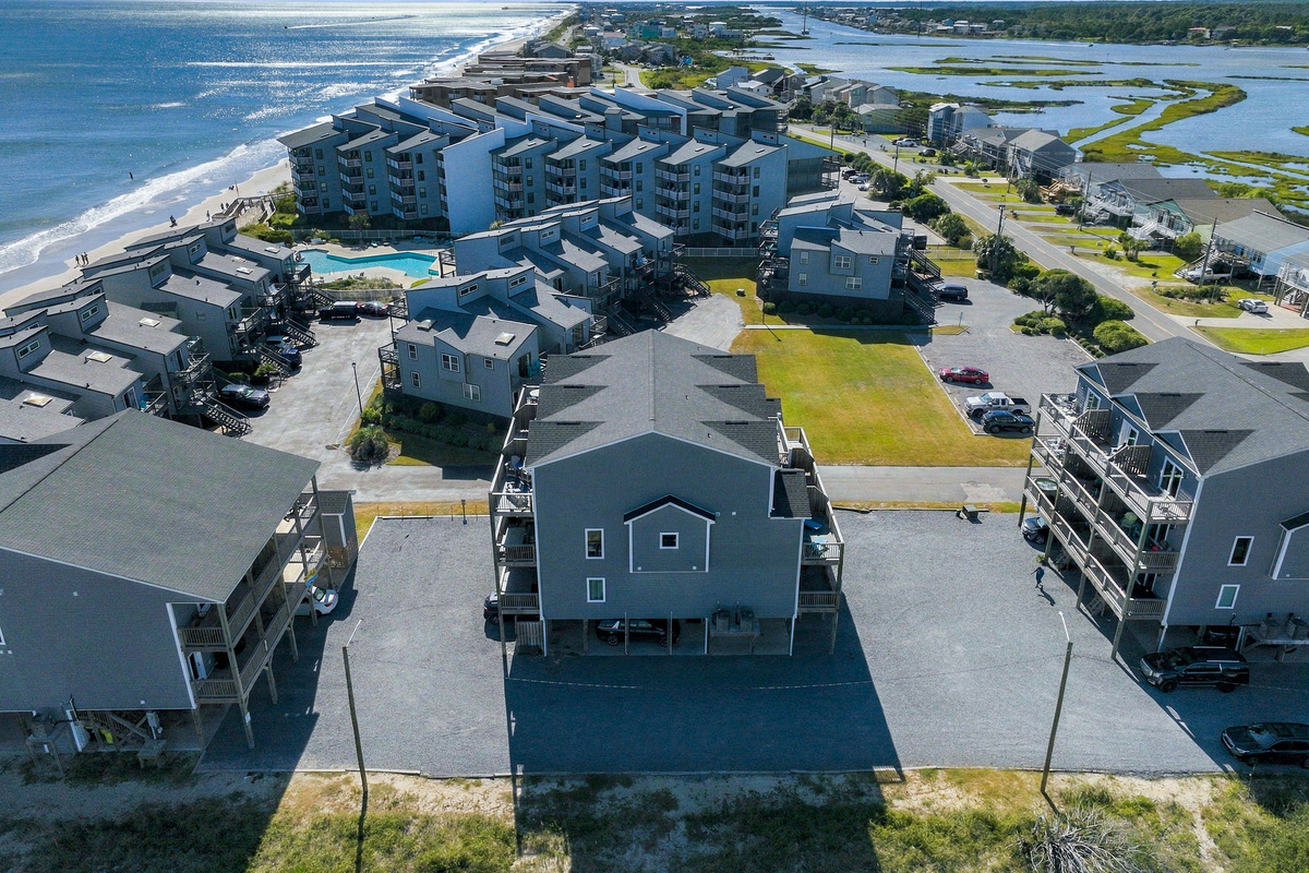 Breathtaking high-altitude drone view highlighting the property's prime location, nestled directly between the Atlantic oceanfront shoreline and serene coastal sound views.   