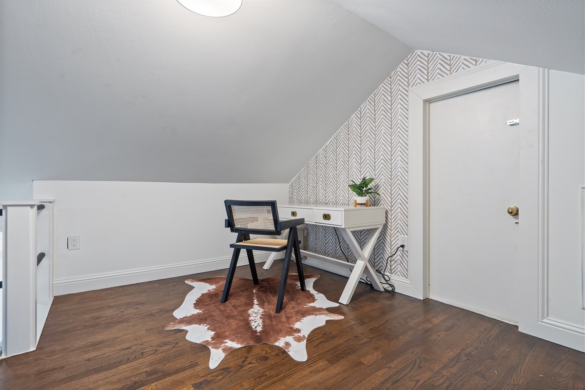 Loft Dedicated Workspace with desk and chair — ideal for remote work and extended stays. Open upper level with hardwood floors, natural light, clothing storage, and high-speed Wi-Fi. Main house.