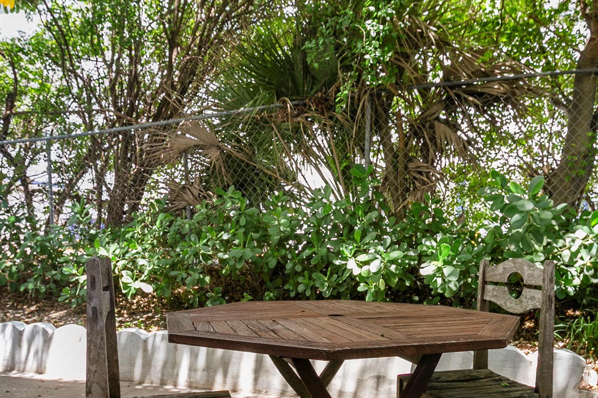 Shaded outdoor seating with a teak table for two, just outside the unit