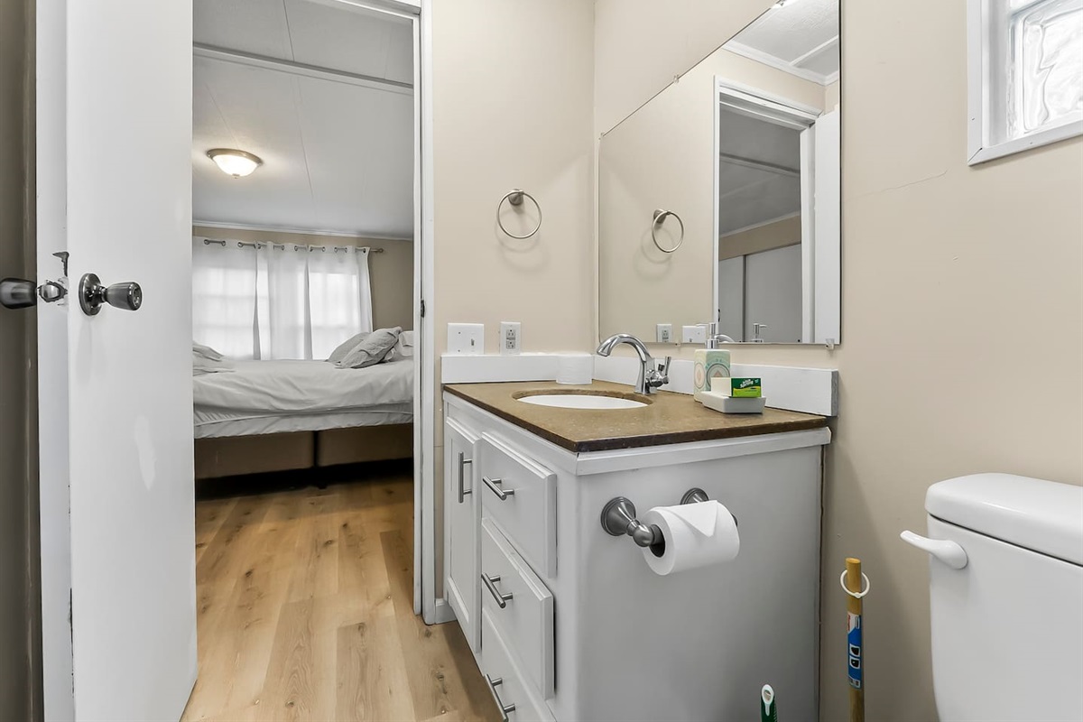 Bright bathroom with a large mirror and easy access from the bedroom.
