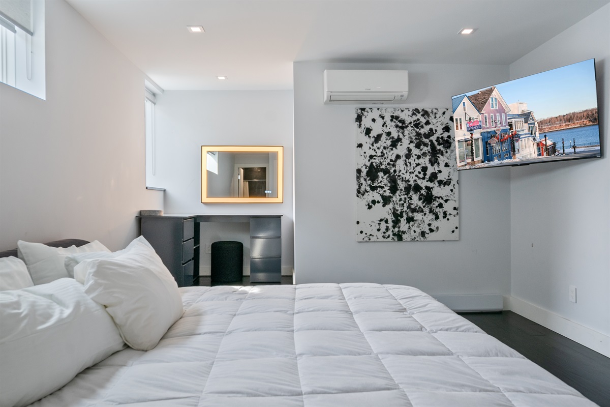 Primary Suite featuring a King bed, dedicated AC, and remote blackout blinds. The modern vanity includes a Bluetooth-enabled light-up mirror for music and getting ready. A quiet, sophisticated sanctuary in the heart of downtown Bar Harbor.