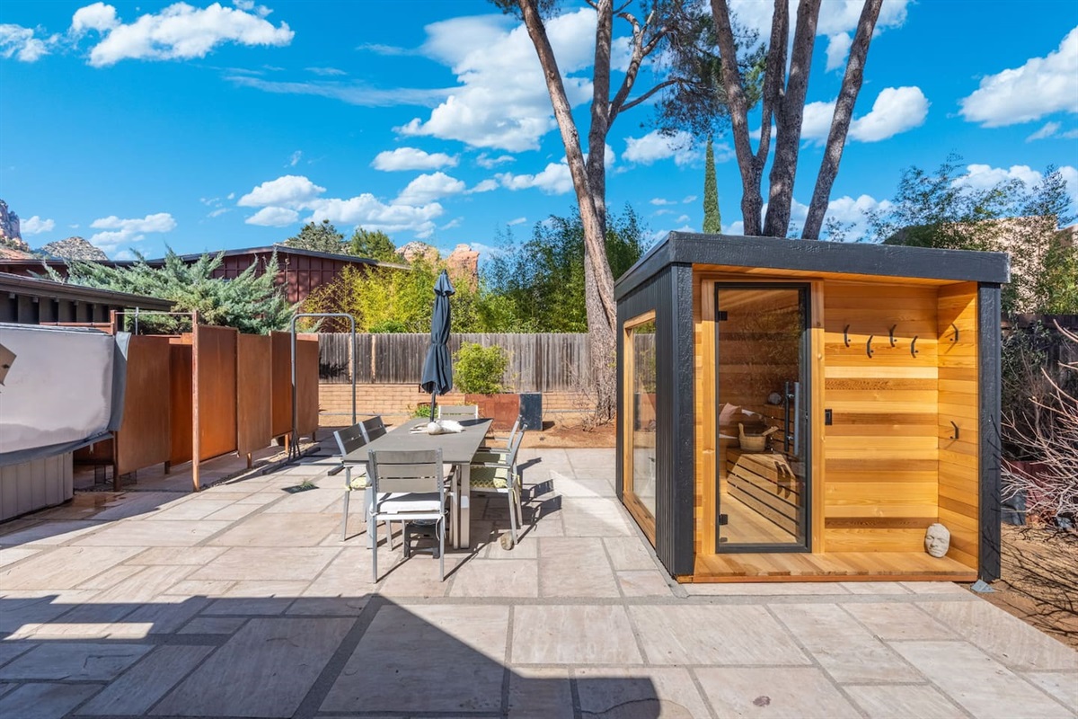 Sun-soaked backyard retreat featuring a sleek private sauna, outdoor shower, and spacious patio with dining area — perfect for relaxing afternoons and evening gatherings under the open sky.