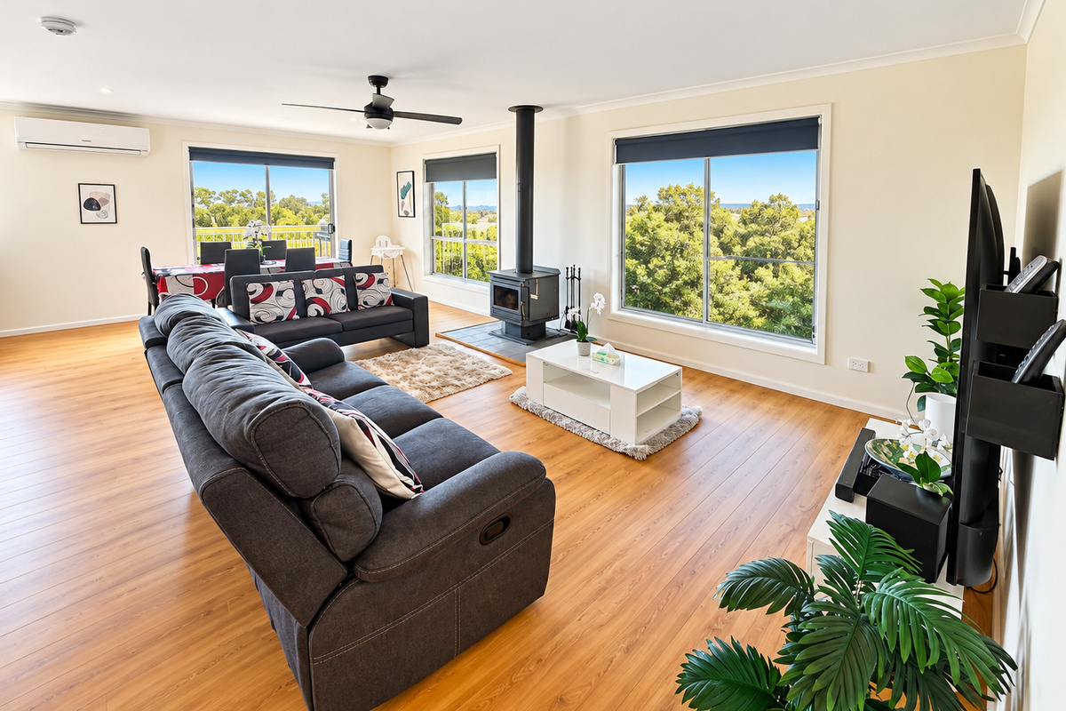 Relax and unwind at Carlenes Getaway in this light-filled open living space, featuring generous seating, a cosy fireplace and leafy views through the large windows.