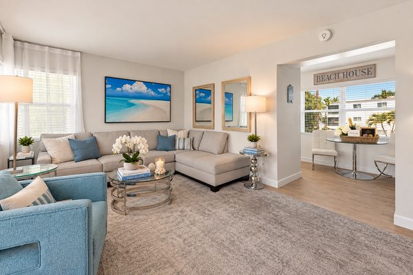 Bright coastal living room with comfortable seating and an open view toward the kitchen and dining area.