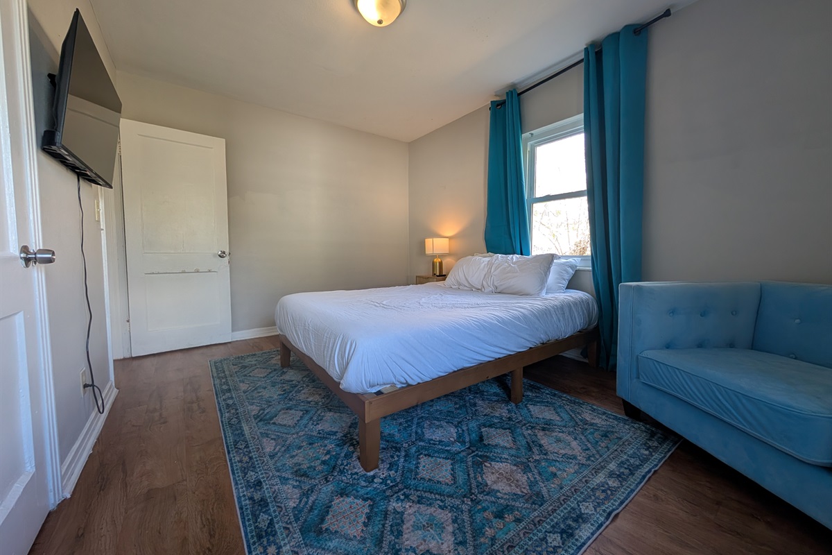 Master bedroom with queen bed, smart TV and chair