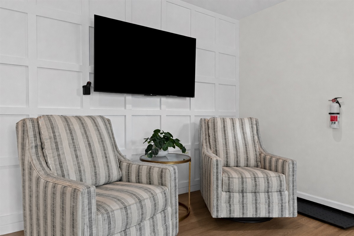 Enjoy a cozy seating nook with plush accent chairs, a smart TV, and modern finishes—perfect for relaxing, reading, or casual conversation.