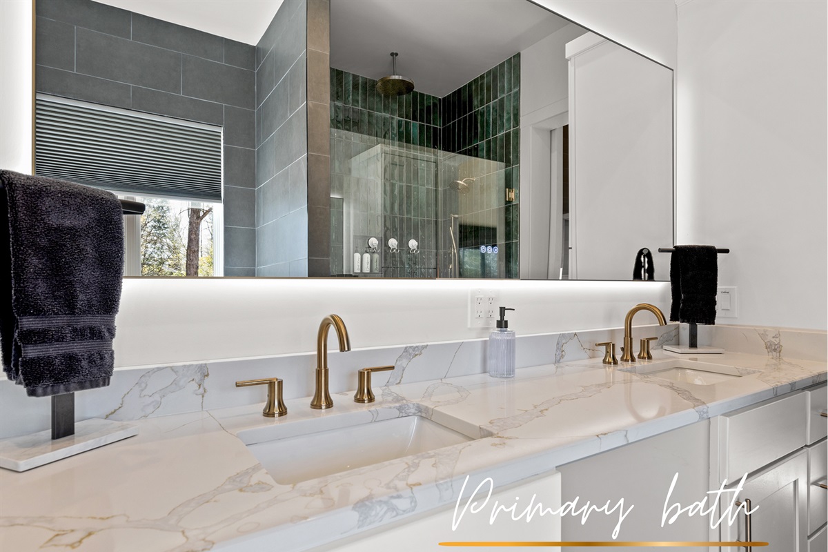 Sleek and modern with a hint of luxe. Those gold fixtures really pop against the cool, dark green tiles. It's bath time with a touch of design!