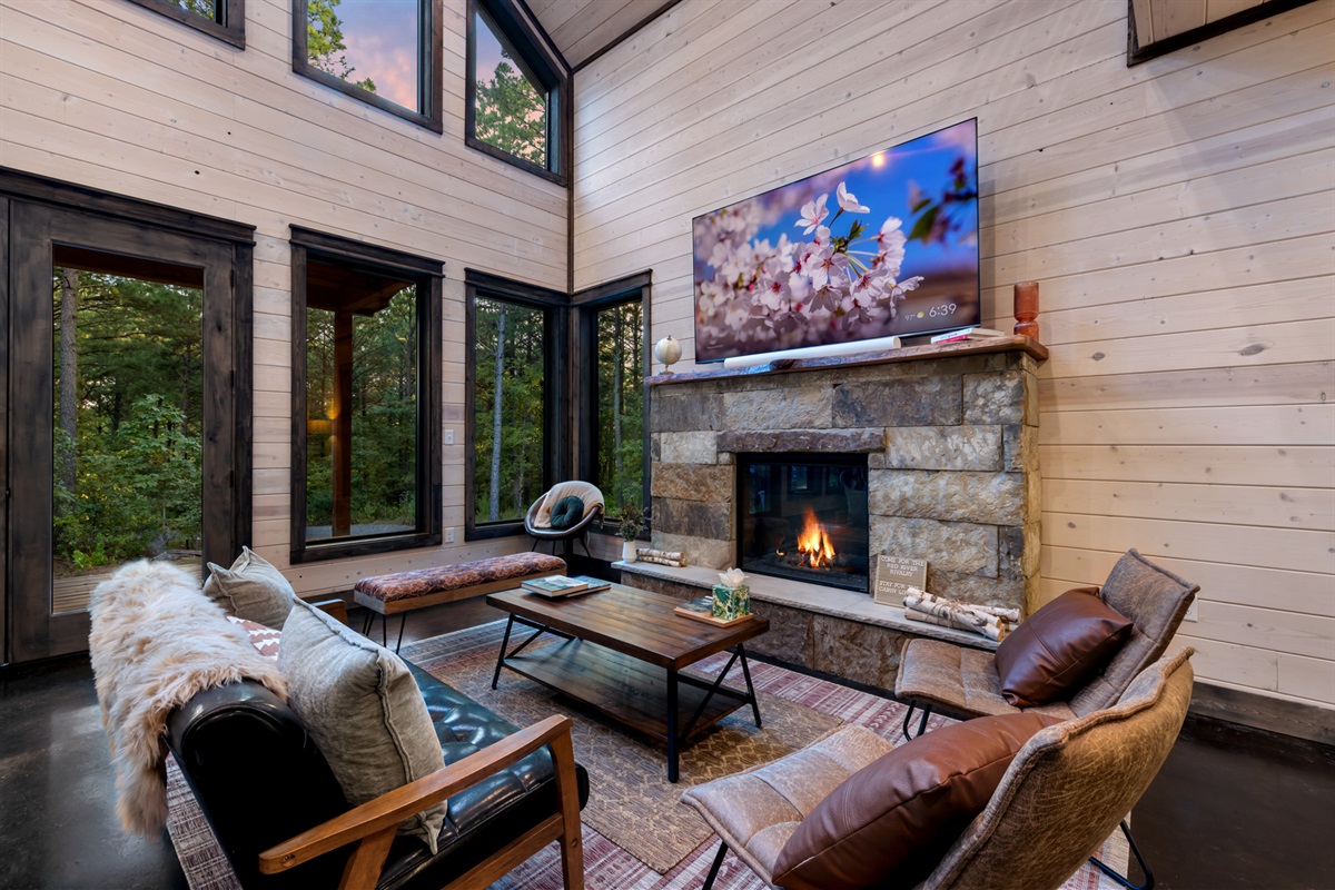 Cozy main living area featuring a comfortable sofa set positioned directly in front of the TV and indoor fireplace, creating the perfect spot for movie nights, relaxation, and gathering together in a warm, inviting setting.