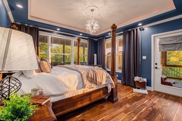 Primary bedroom with king four-poster bed, blue accent walls and door to the deck