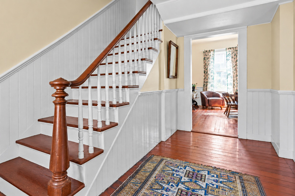 A glimpse of how Heritage House flows: the historic staircase rises from the central hall to 2 bedrooms and bath, the living room is at right and dining room and kitchen, beyond.  