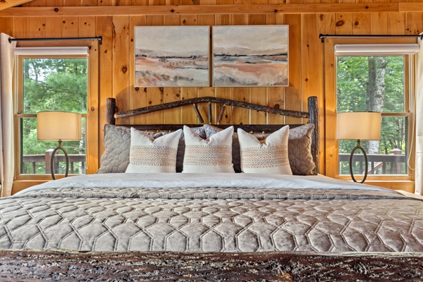 The upstairs king bedroom is spacious and features comfortable bedding, rustic charm, and a calm, inviting place to unwind.