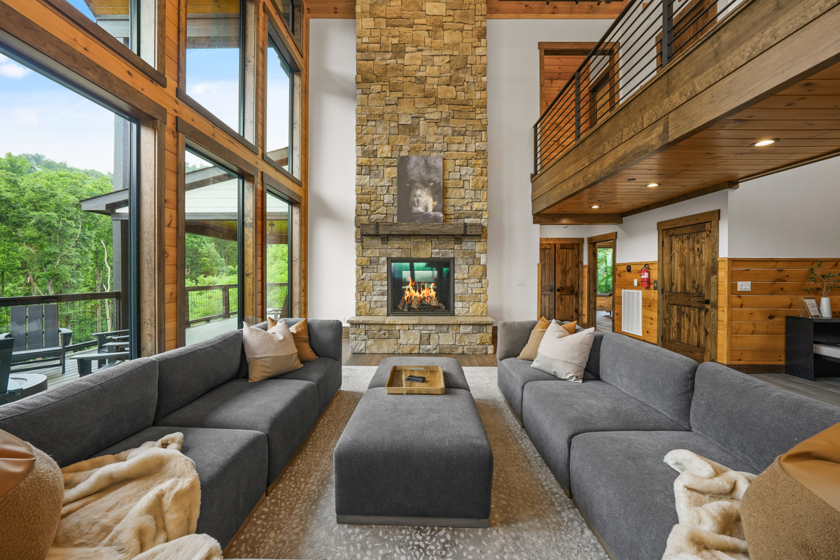 Gather beneath 30-foot vaulted ceilings surrounded by a wall of windows. Relax on the large sectional sofa beside the luxury fireplace with stunning floor-to-ceiling stone, creating a warm and unforgettable mountain lodge atmosphere.