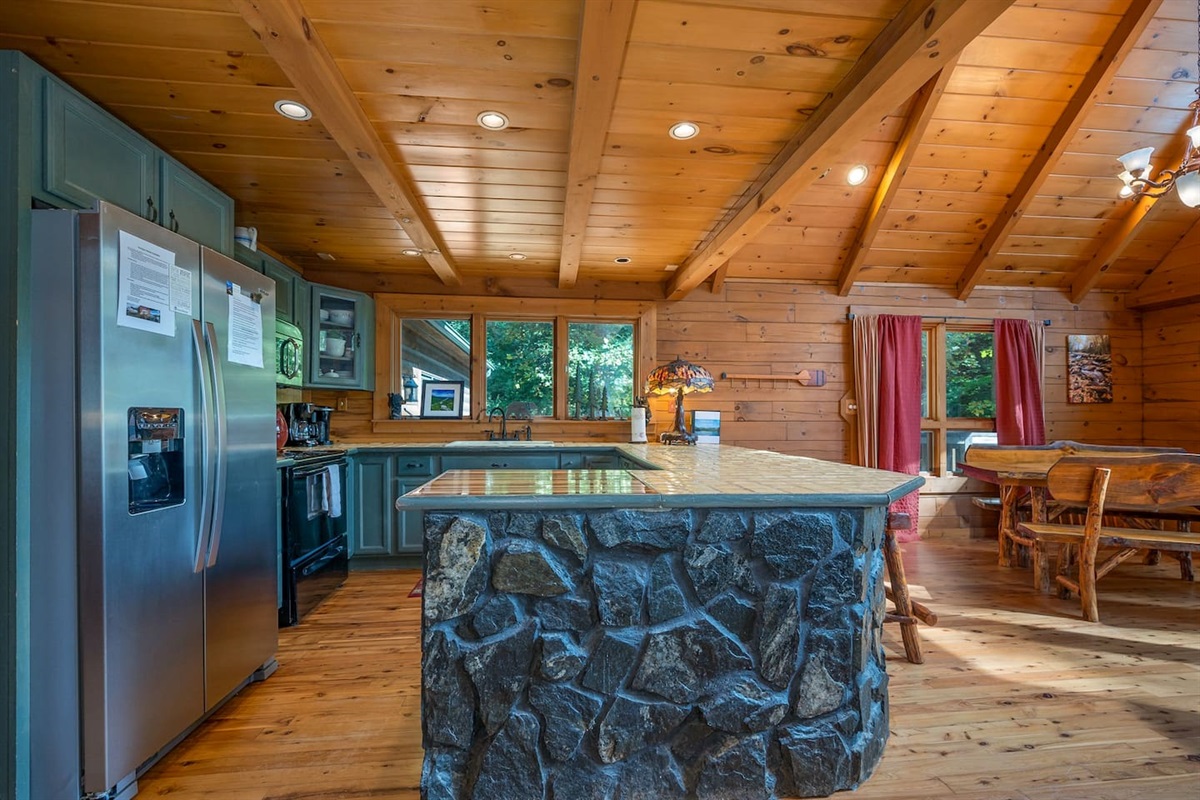 Fully stocked kitchen with bar and bar stools and dining table that seats 8-10