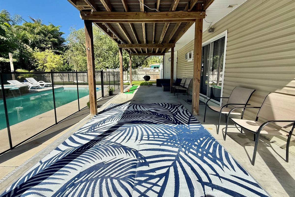 A spacious covered deck ideal for sipping drinks, reading, or watching the kids play in the pool.