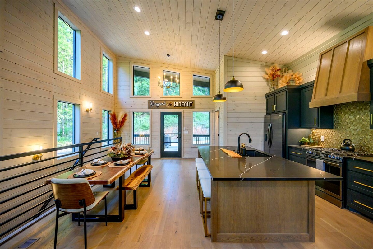 Large open kitchen features a huge island with bar seating next to the custom live edge dining table.