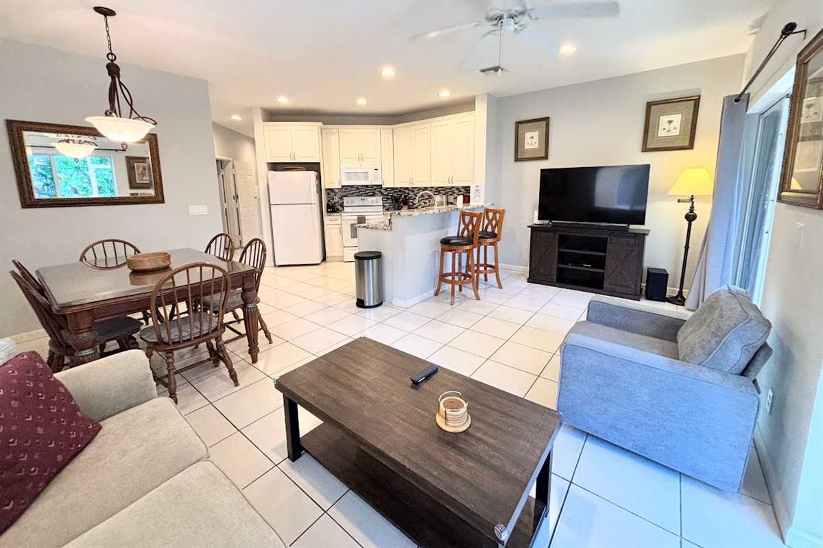 Bright open-concept living, dining, and kitchen area with tile flooring, comfortable seating, and a fully equipped kitchen.