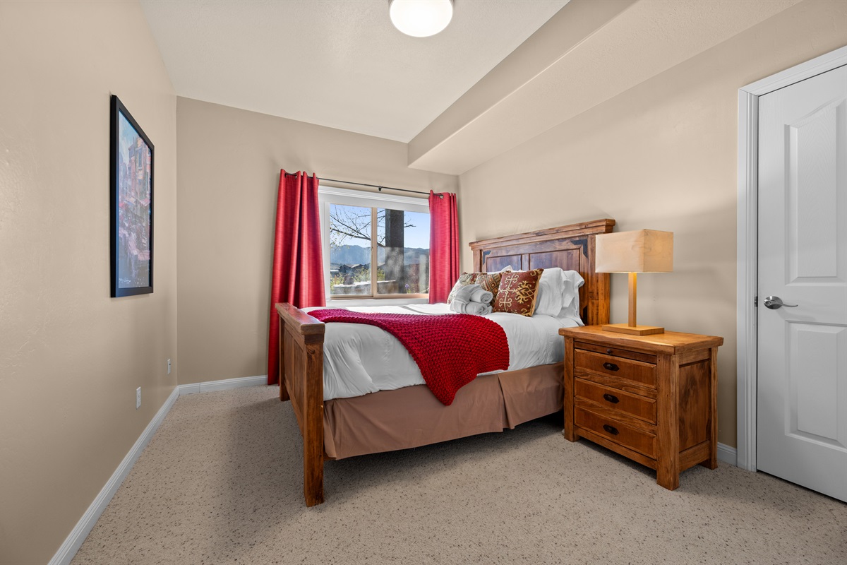 An inviting bedroom with a queen bed, warm décor, and natural light.